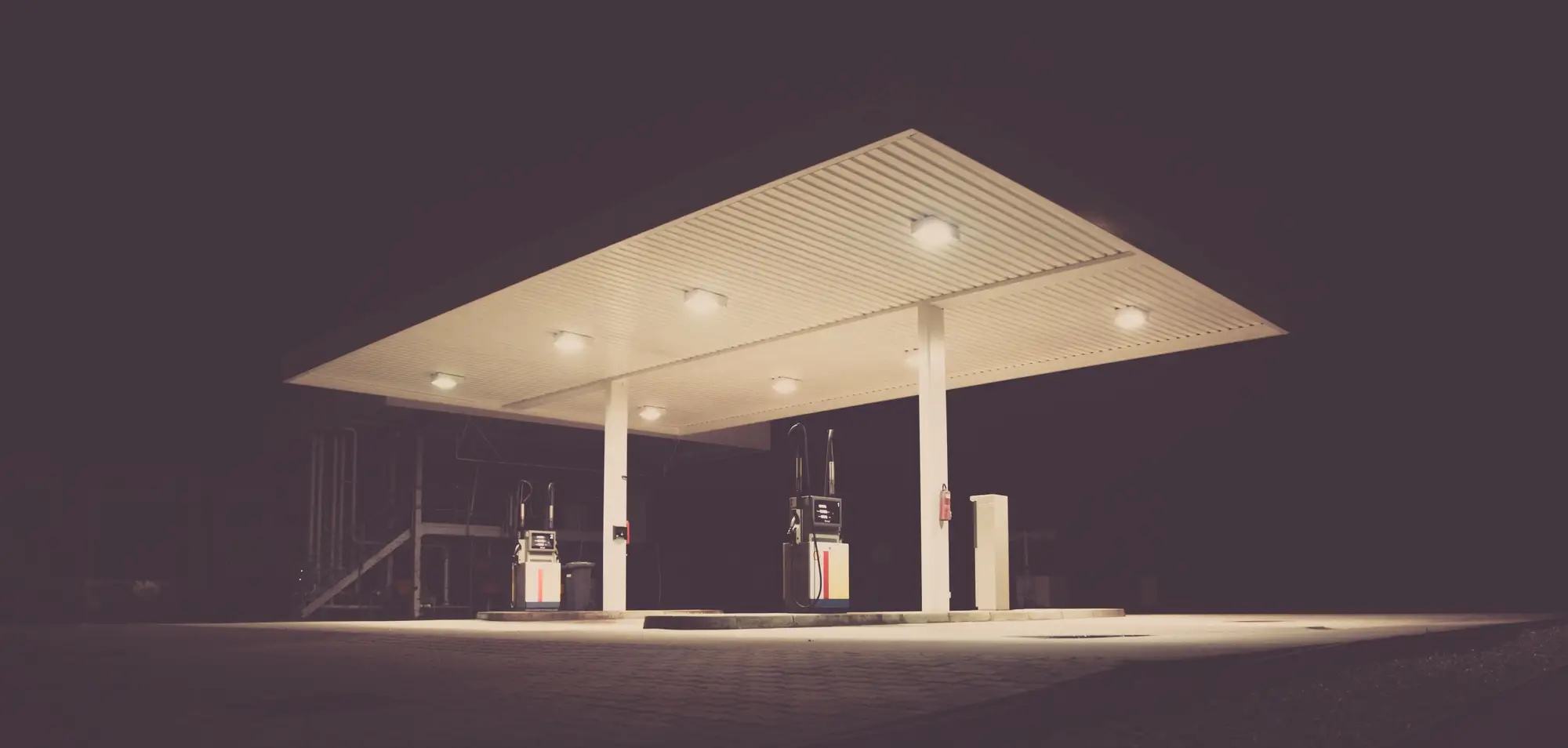 An empty, unbranded fuel station canopy lit at night over a single pump island
